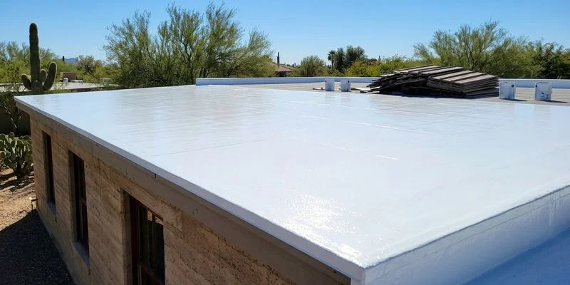 Completed bright white reflective roof coating on a Tucson home with clear blue desert sky above